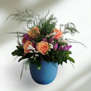 Peach roses with purple statice and white filler flowers in a lush green bouquet in a blue vase. (informative)