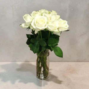 Bouquet of white roses in a clear glass vase on a light gray countertop.