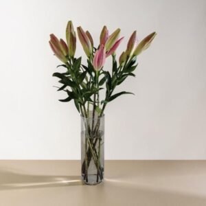 Glass vase with pink lilies on a light beige tabletop
