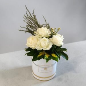 White rose bouquet in a white hatbox with gold trim on a gray table surface, for a gift.